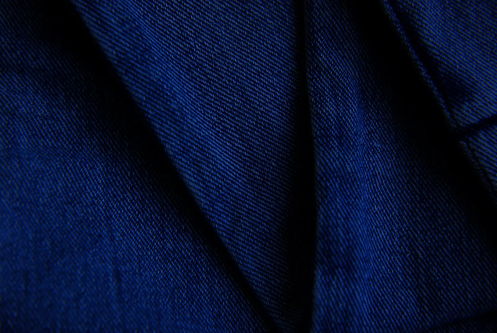 Close-up of folded dark indigo denim, a cotton twill, with the diagonal twill wale running across the cloth