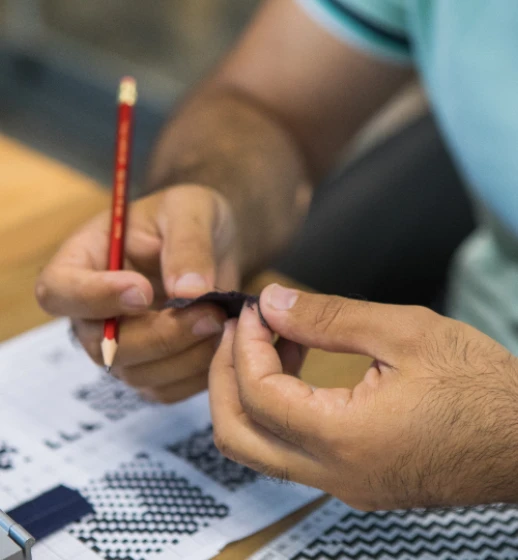 A designer at Donear checking a fabric swatch against a weave design sheet
