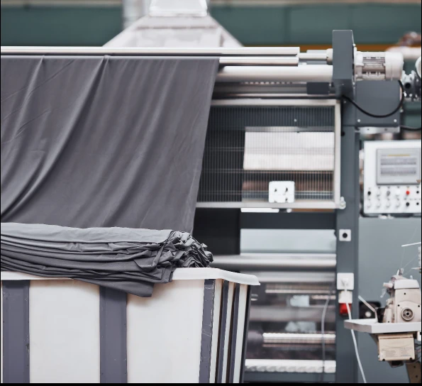Grey fabric running through a finishing machine at Donear