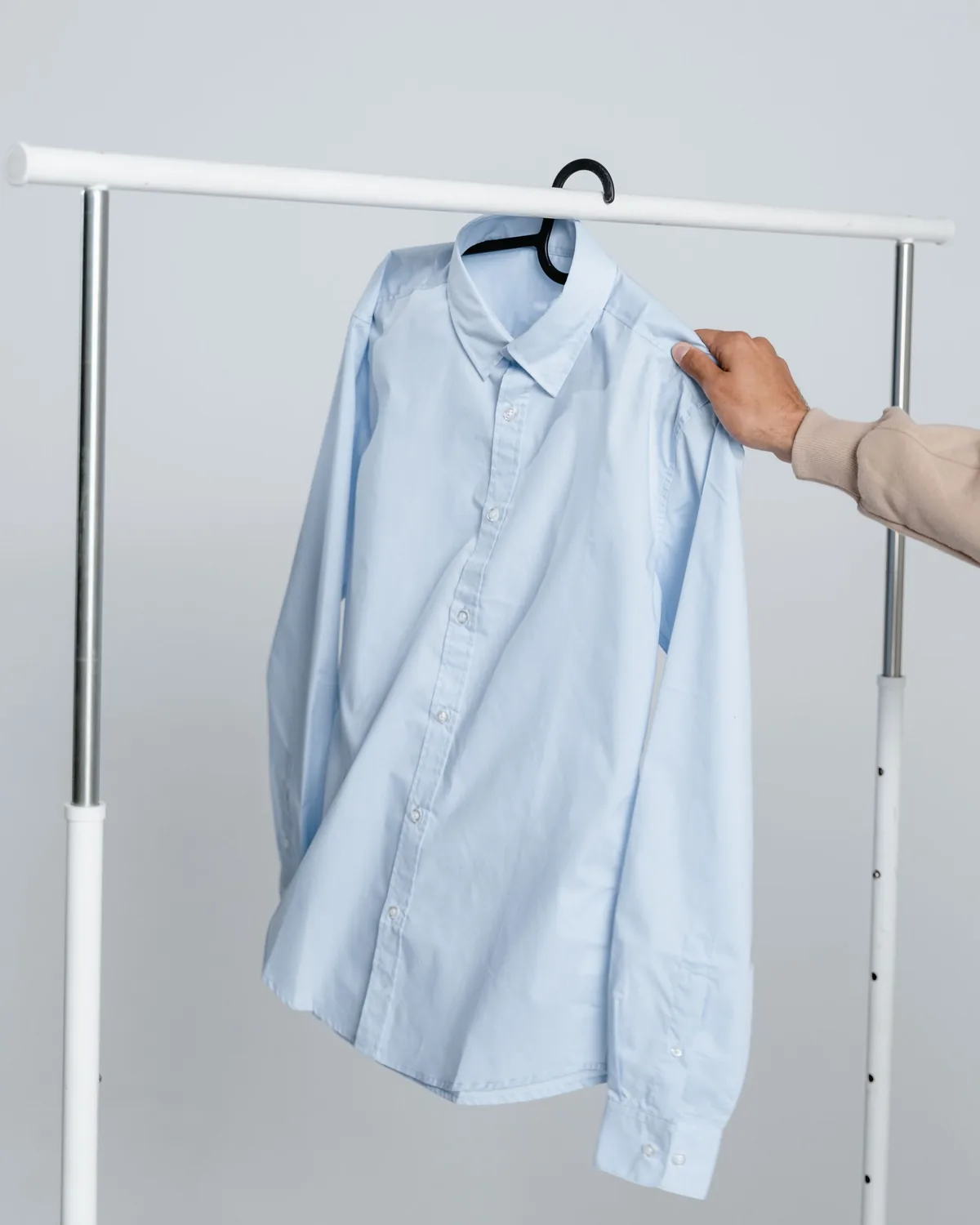 Light blue long-sleeve button-front shirt with point collar and two-button cuffs, on a hanger on a white clothes rail
