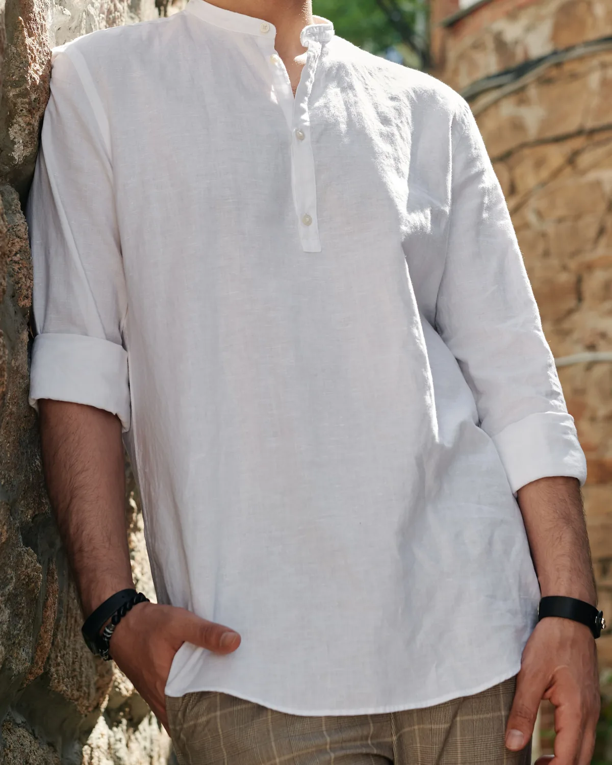 White linen popover shirt with band collar and rolled sleeves, worn and shown from the neck down